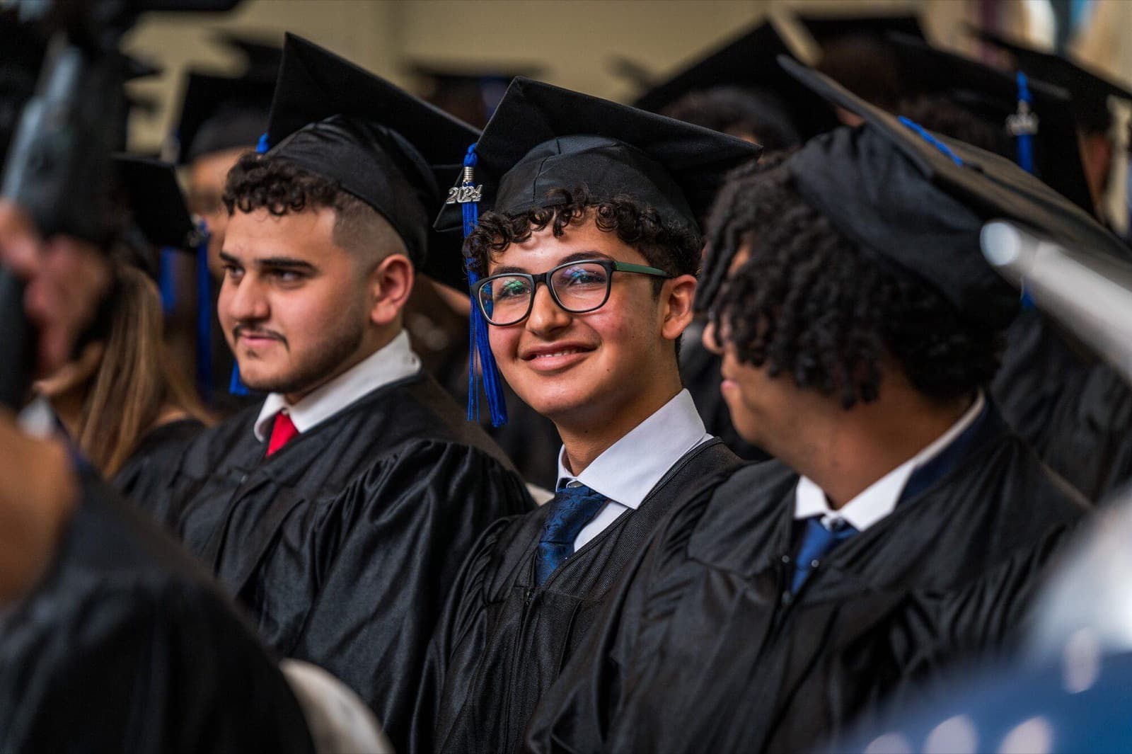 Three smiling graduates in gowns and mortarboards.
